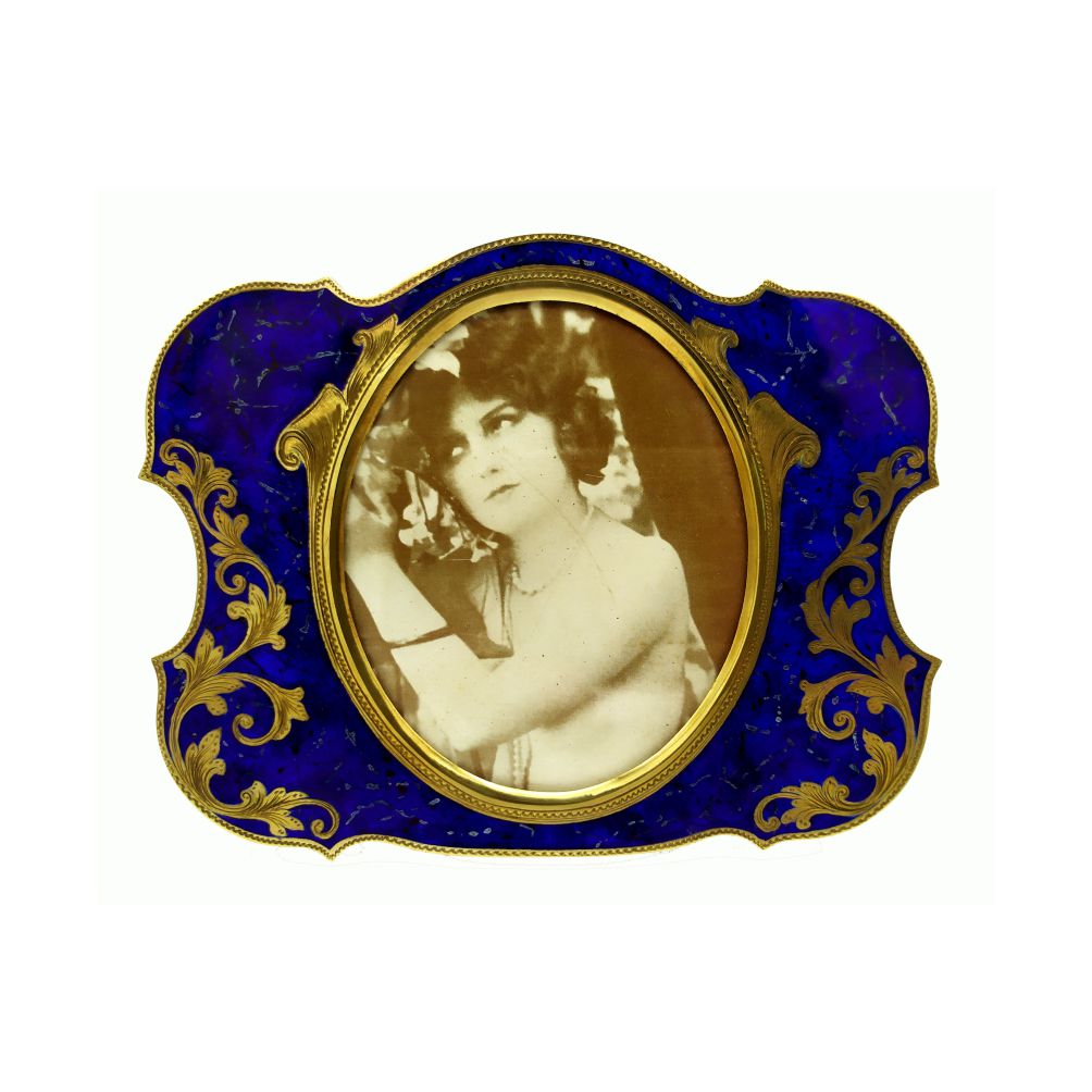 1976-7015 - Shaped photoframe with oval interior in 925/1000 sterling silver gold plated with hand-engraved ornaments and fire-painted enamel as lapis lazuli stone. Baroque style 1700s. External measurements cm. 11.5 x 14.5 interior cm. 7.5 x 9. Designed by Franco Salimbeni in 1985 and produced in the Salimbeni factory with handwork by skilled artisans with a thick plate suitable for sustaining numerous firings of enameling by high fire at about 800° C.