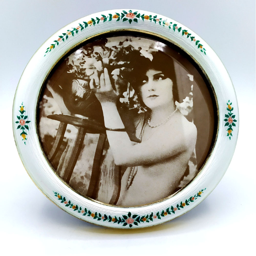 0076-2944 - Round photo frame in 925/1000 sterling silver gold plated with translucent fired enamel on guillochè and hand-painted miniature of garlands of flowers in the late 1800s Viennese Art Nouveau style. External diameter cm. 14 internal cm. 11. Weight gr. 123. Designed by Franco Salimbeni in 1970 on inspiration from previous frames also manufactured in the Salimbeni company headquarters with manual processing by skilled artisan artists with a thick plate suitable for supporting numerous high-fire enamel firings at around 800° C.