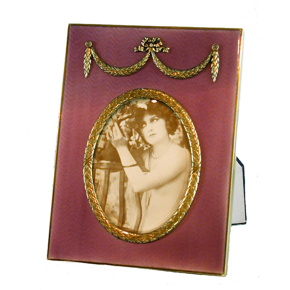 0762-4345 – External rectangular oval photo frame in gilded 925/1000 silver with translucent fired enamel on guilloche and French Empire Napoleon III style ornaments. External measurements cm. 15 x 20 internal oval cm. 8.5 x 11.2, weight g. 510. Designed by Franco Salimbeni in 1972 on the inspiration of objects of the time and produced in various examples of different colours, always in the headquarters of the Salimbeni company, with manual workmanship by talented artisan artists, with a high thickness plate suitable for supporting numerous cooking of high-fire enamelling at approximately 800° C.