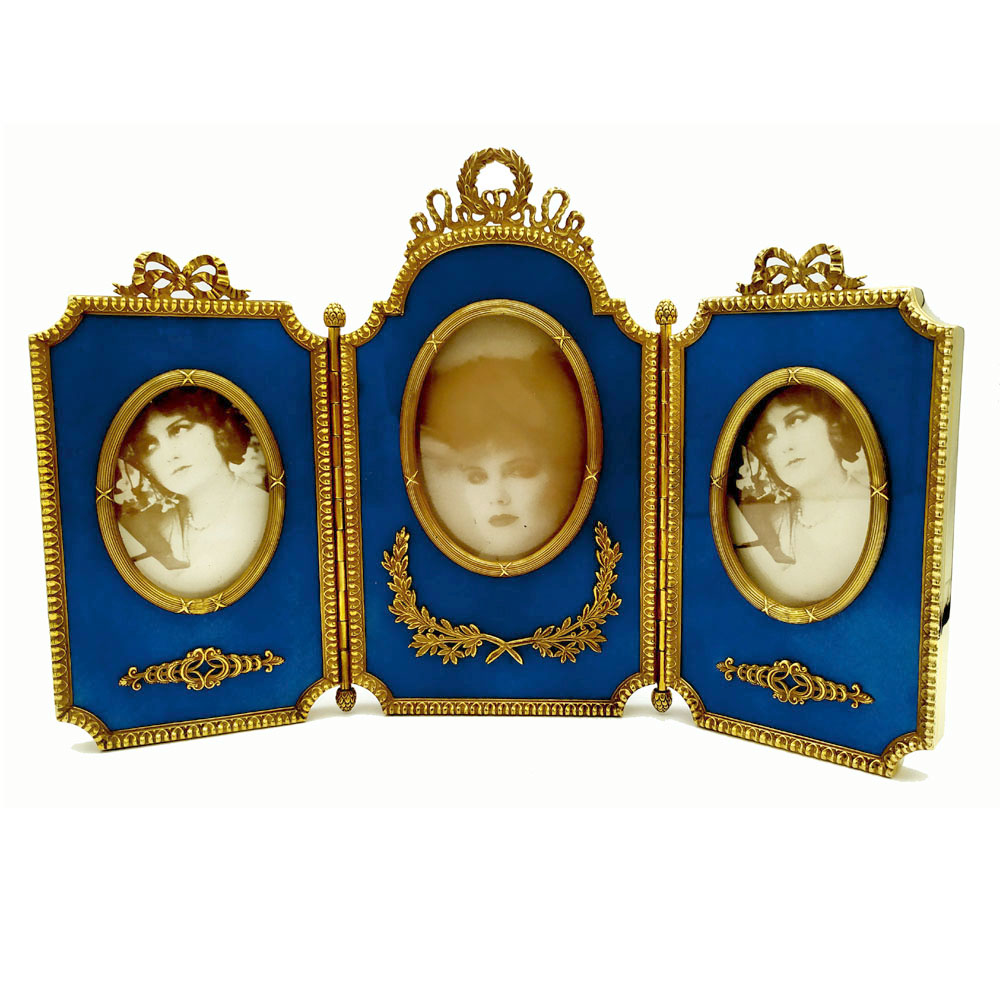 1865-6729 - Triptych hinged shaped frame for 3 photographs in 925/1000 sterling silver gold plated with translucent fired enamel on guillochè with borders and ornaments in French Louis XVI Empire style. Open measurements 27.7 x 18.2 cm. Weight gr. 877. Designed by Giorgio Salimbeni in 1981 and produced in the Salimbeni factory by hand by skilled craftsmen with a thick plate suitable for sustaining numerous enameling firings at high heat at about 800° C.