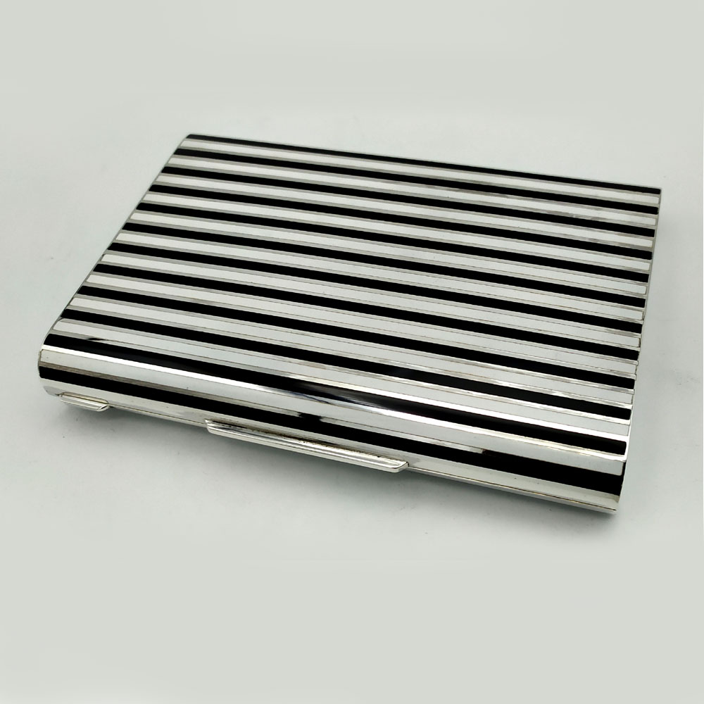 4663-5351 - Large rectangular table box with long rounded sides in 925/1000 sterling silver with fire-enamelled stripes in Art Deco style. With “lost” hinge, i.e. semi-invisible. Dimensions cm. 10.5 x 15 x 2.3. Weight gr. 548. Inspired by drawings by Louis Cartier from the early 1900s in Art Deco style and recreated for Cartier USA in the 1980s, manufactured in Florence in the Salimbeni company headquarters with completely manual execution by artisan artists with thick and thick slabs reinforcements suitable for supporting numerous high-fire enamelled firings at about 800° C.