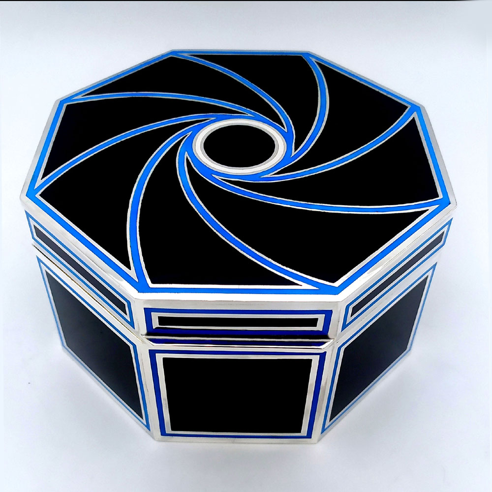 4906-5635 - Octagonal table box in 925/1000 sterling silver with fire-enamelled Art Deco design. Dimensions diameter cm. 15.8 high cm . 8.2. Weight gr. 974. Designed by Giorgio Salimbeni for Cartier USA in the 1980s, inspired by objects designed by Louis Cartier around 1920 and manufactured in Florence in various specimens, also in parure with other objects and in different colors, in the headquarters by the Salimbeni firm with completely manual execution by artisan artists with thick slab and large reinforcements suitable for withstanding numerous high-fire enamelled firings at about 750°